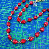Necklace with red ladybug beads on a blue grid background