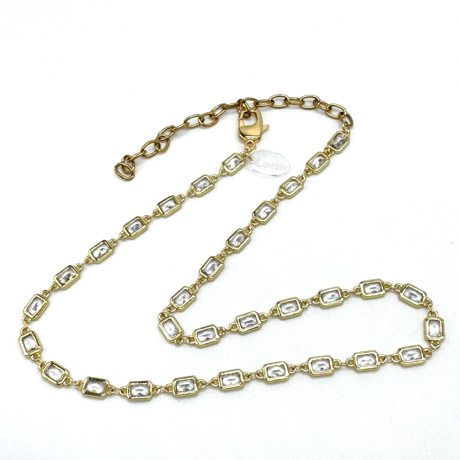 Gold chain necklace with clear stones on a white background