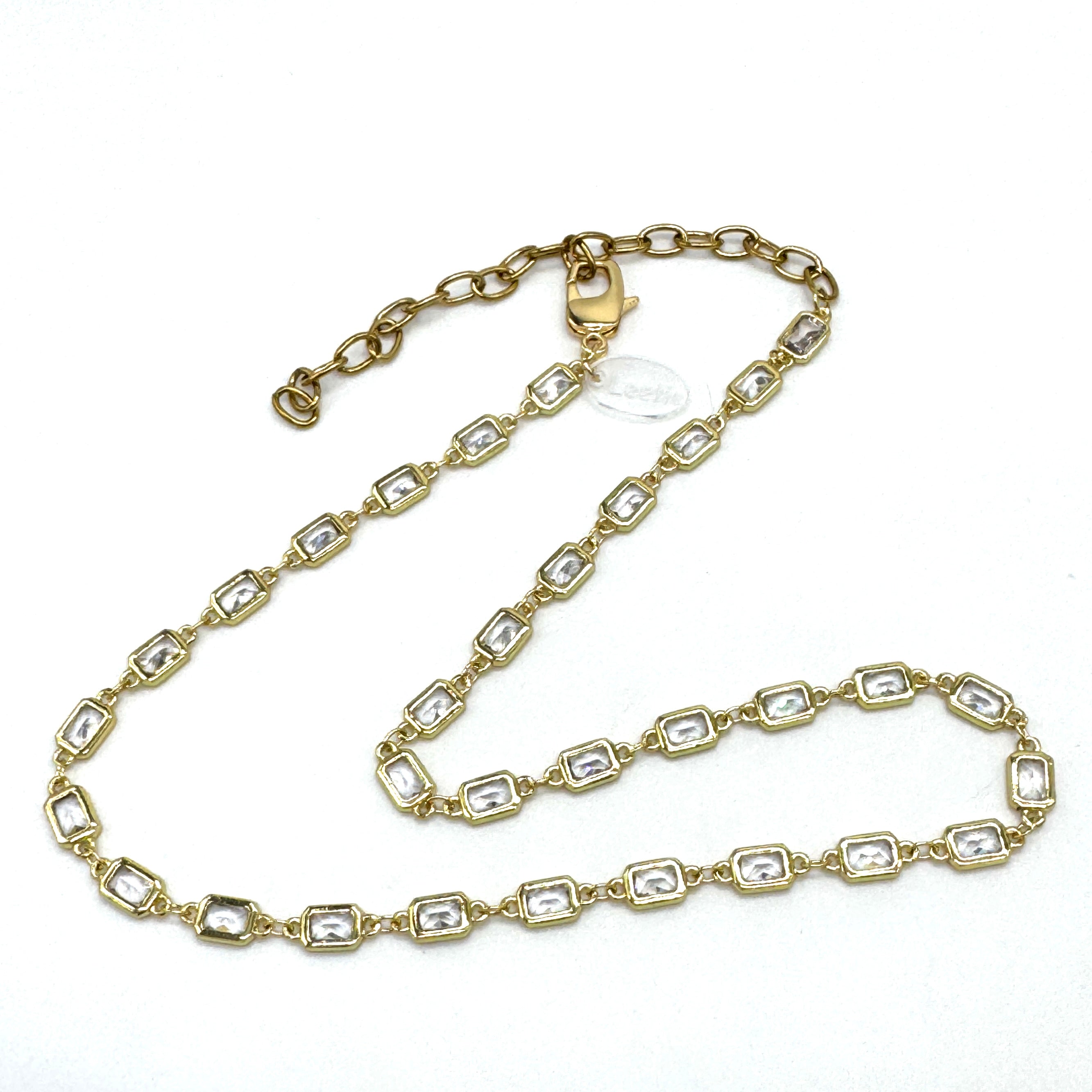 Gold chain necklace with clear stones on a white background