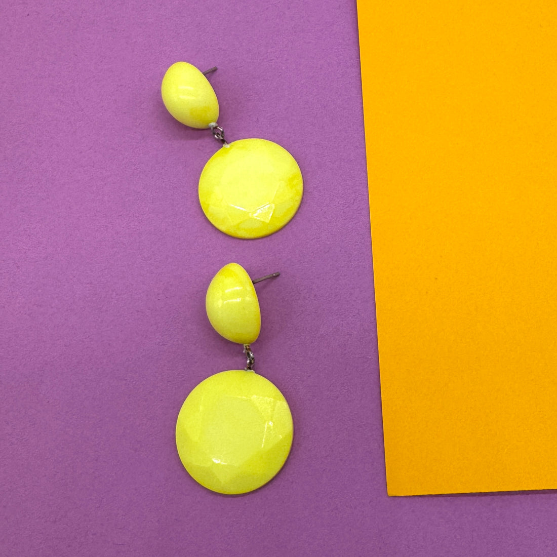 Yellow earrings on a purple and orange background