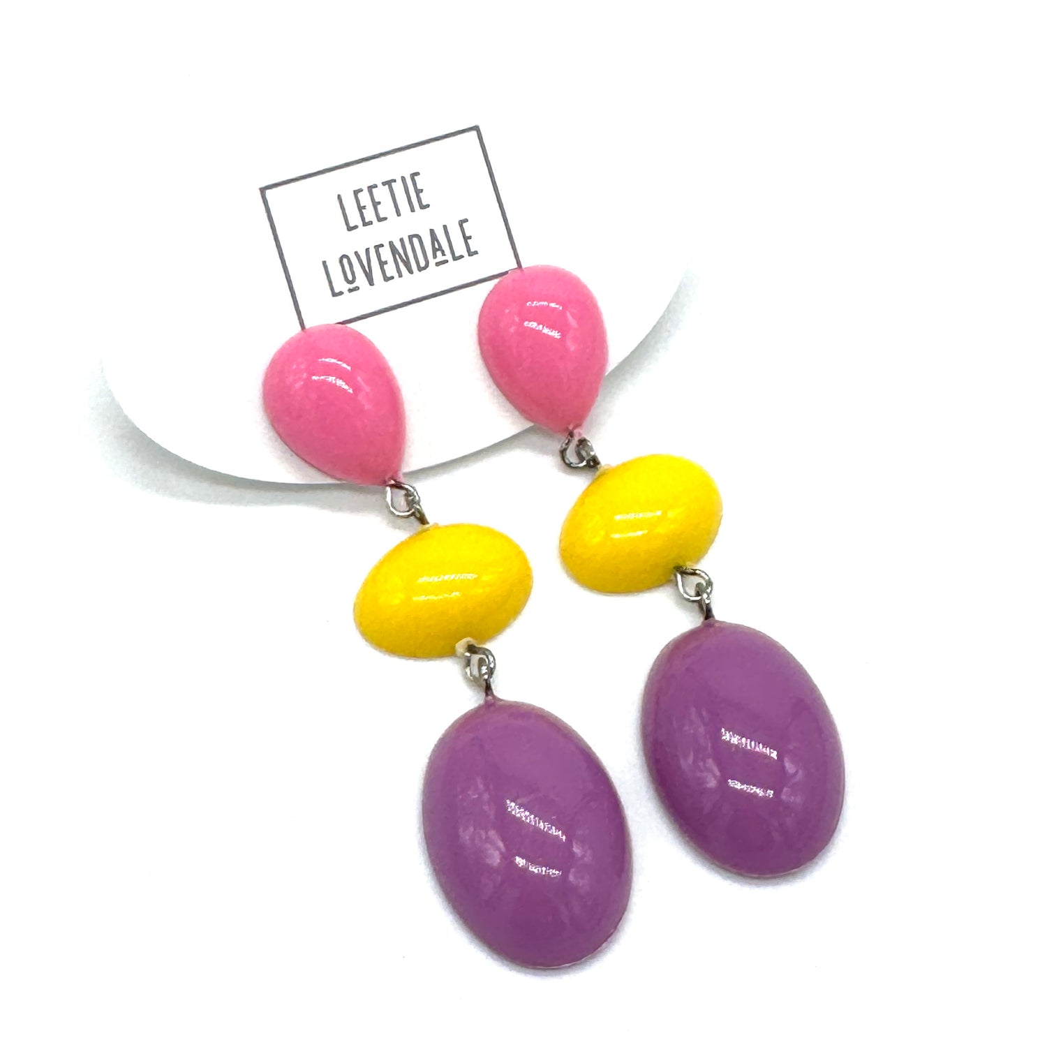 Colorful earrings with pink, yellow, and purple beads on a white background with &