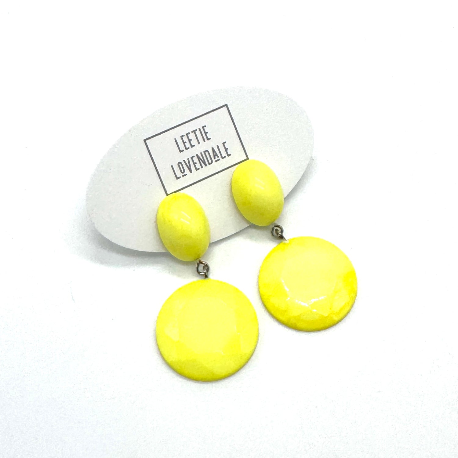 Yellow earrings on a white card with &