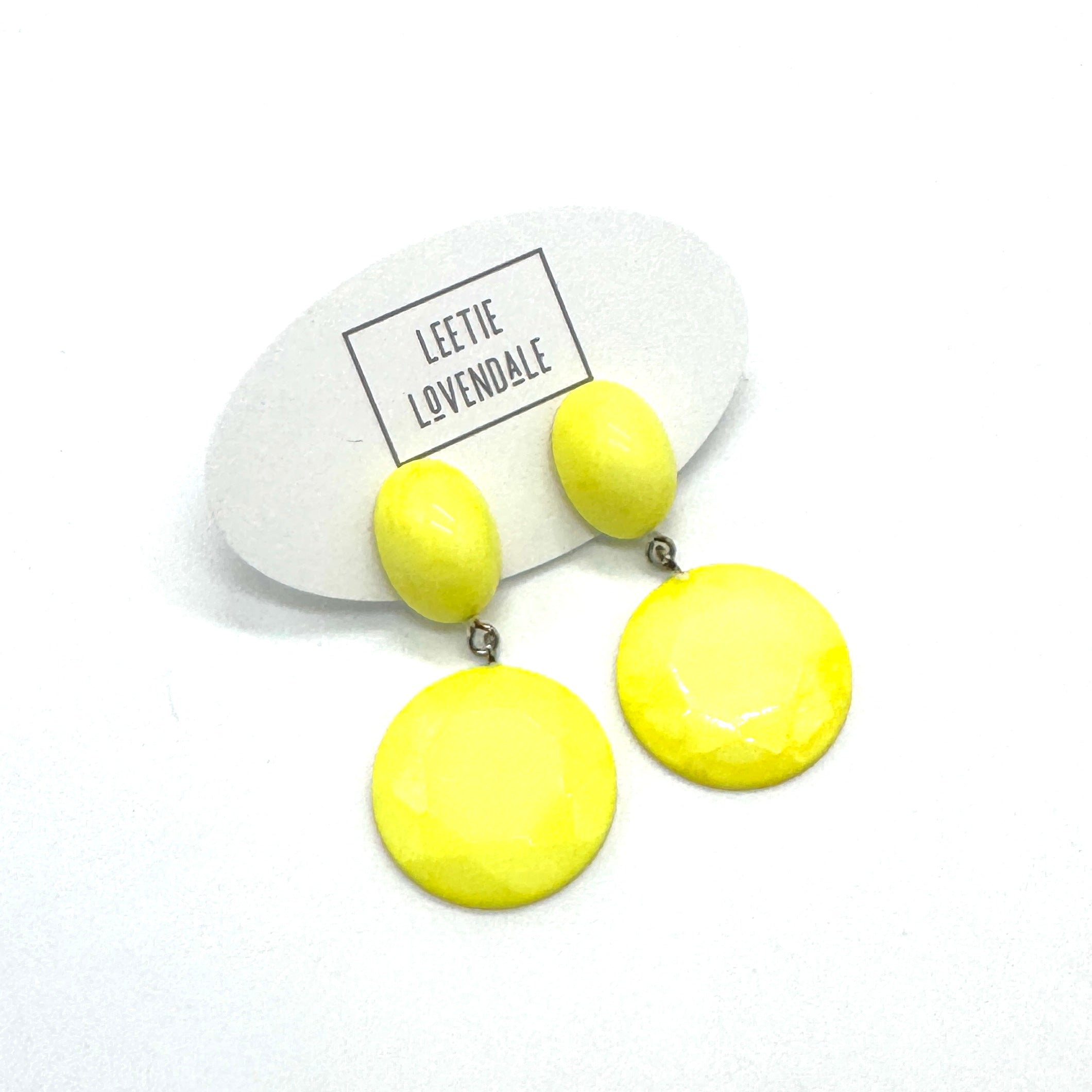Yellow earrings on a white card with &