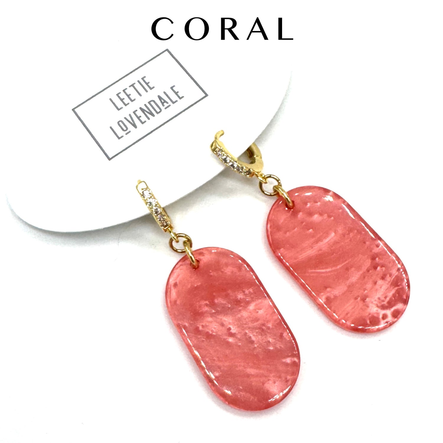 Pink earrings with gold hooks on a white background, featuring the brand &