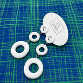 White circular earrings on a blue and green checkered background