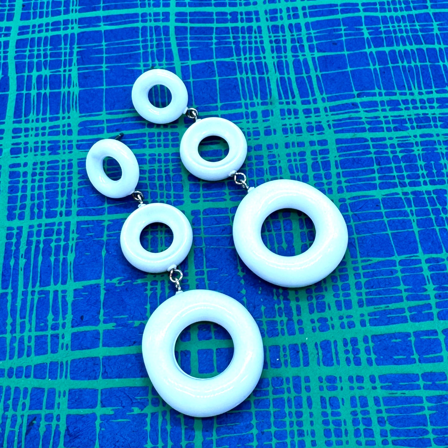 Set of white circular earrings on a blue textured background