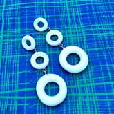 Set of white circular earrings on a blue textured background