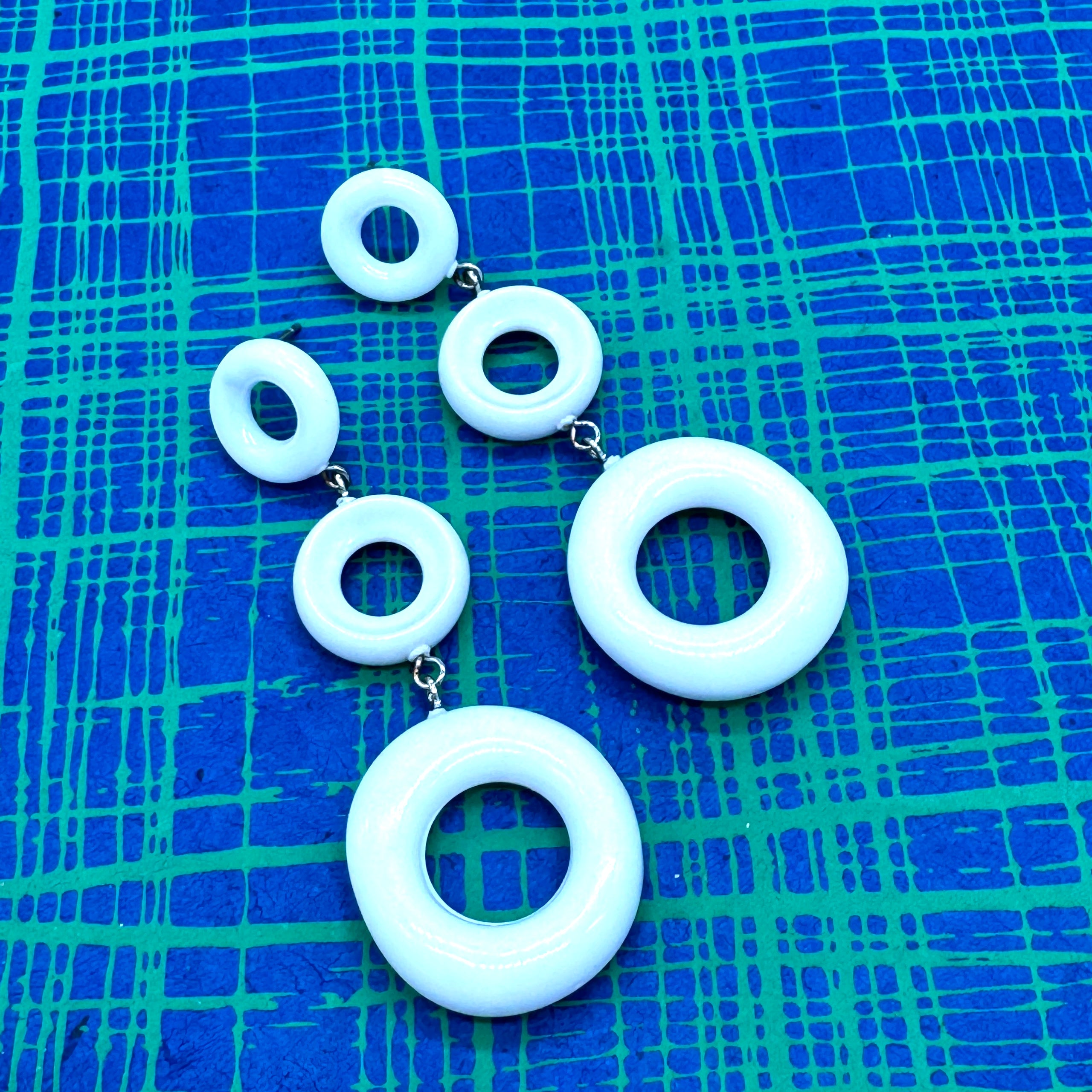 Set of white circular earrings on a blue textured background