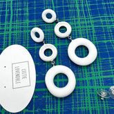 White ring earrings on a blue and green patterned surface with &