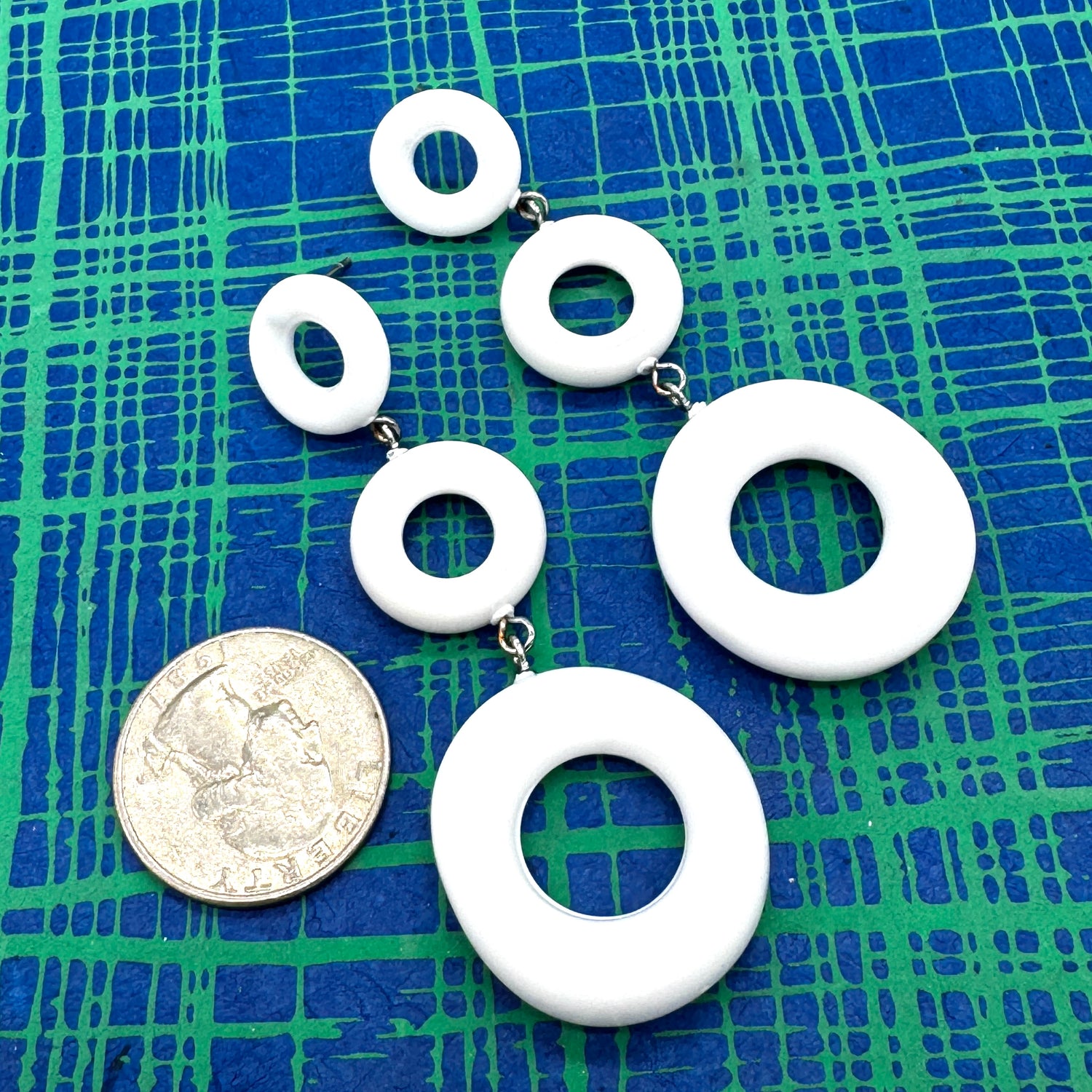 White circular earrings on a blue and green checkered background