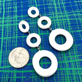 White circular earrings on a blue and green checkered background