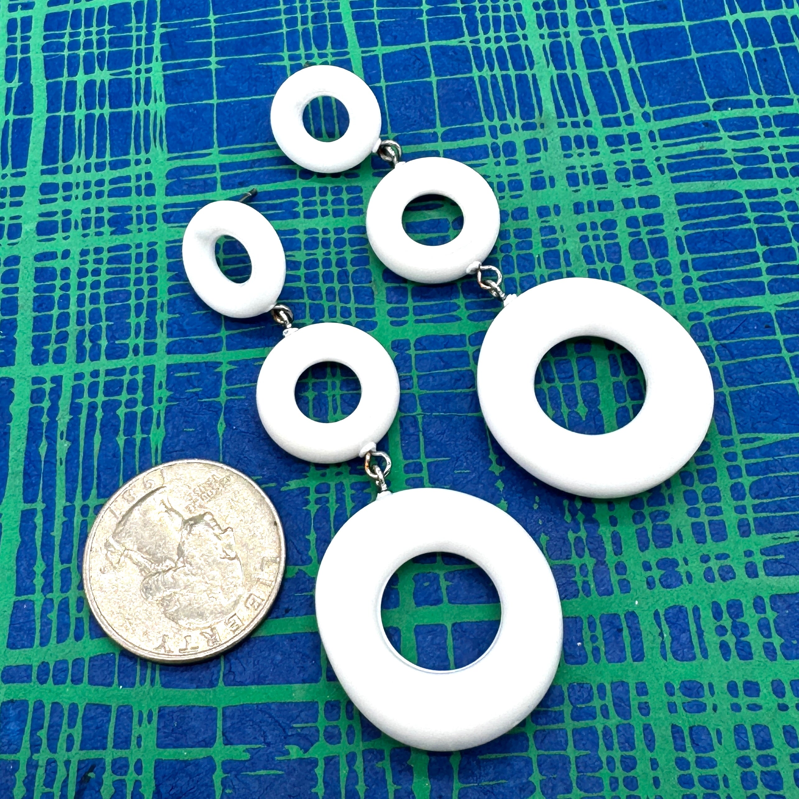 White circular earrings on a blue and green checkered background