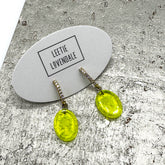 Yellow earrings on a branded card with a textured surface background