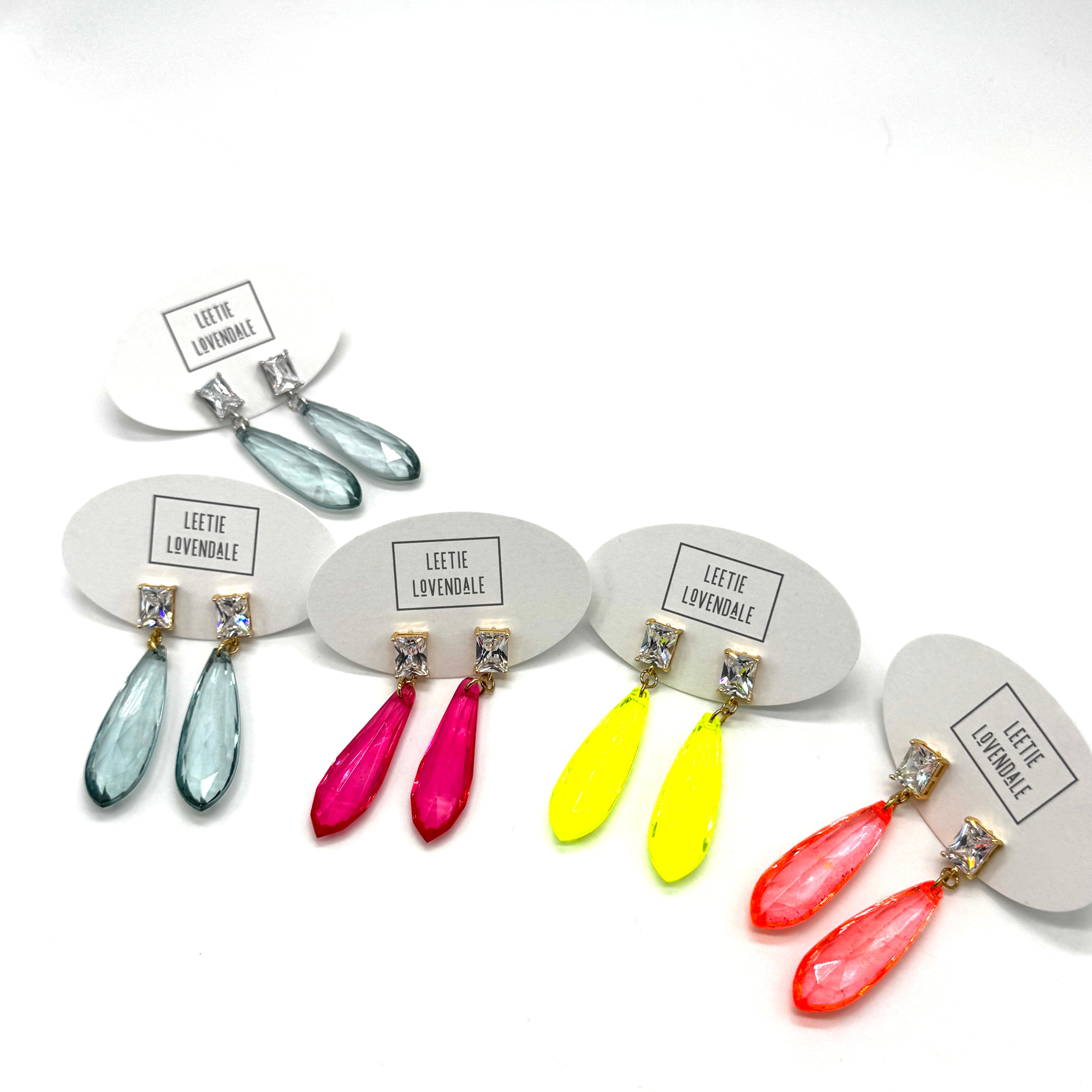 Colorful teardrop earrings on display with name tags.
