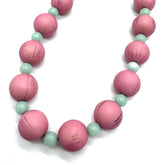 Necklace with pink and light green beads on a white background