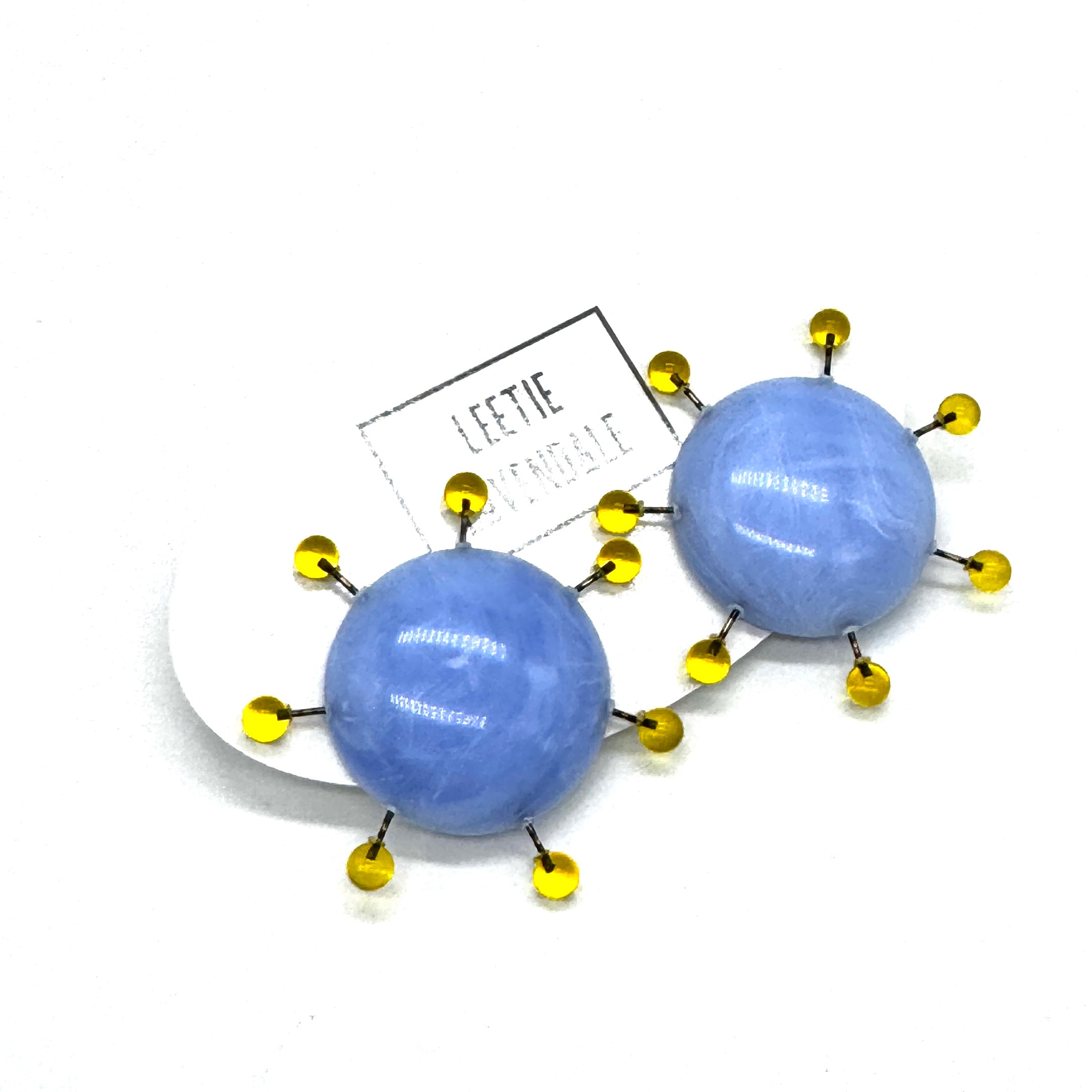 Blue spherical earrings with yellow accents on a white background