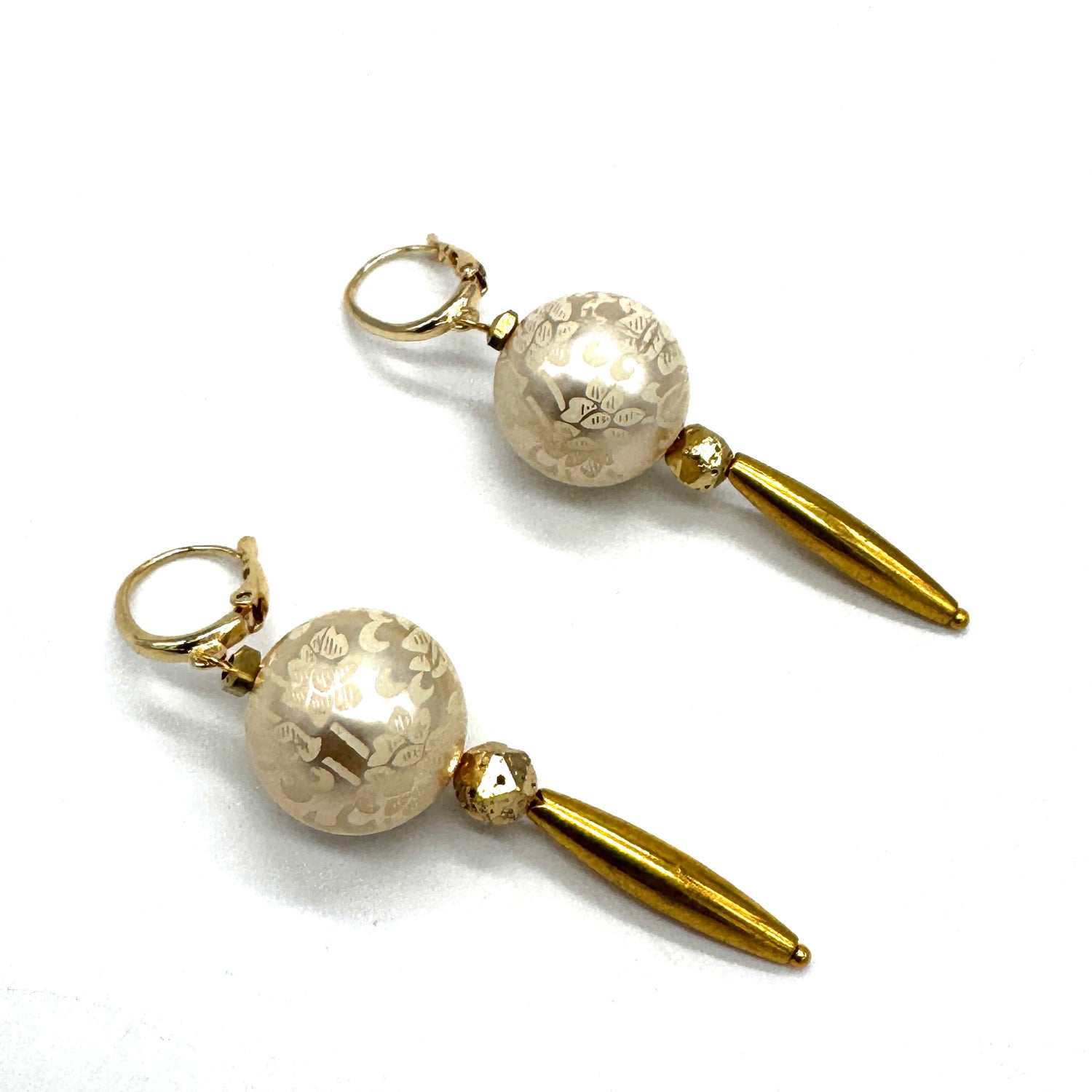 Dangle earrings with floral cream colored beads and golden accents on a white background.