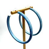 Large crackled blue lucite hoop earrings on a gold stand.