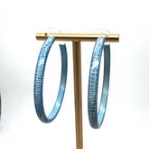 Large crackled blue lucite hoop earrings on a gold stand.