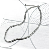 Adjustable silver snake chain necklace on a patterned background.