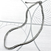 Adjustable silver snake chain necklace on a patterned background.