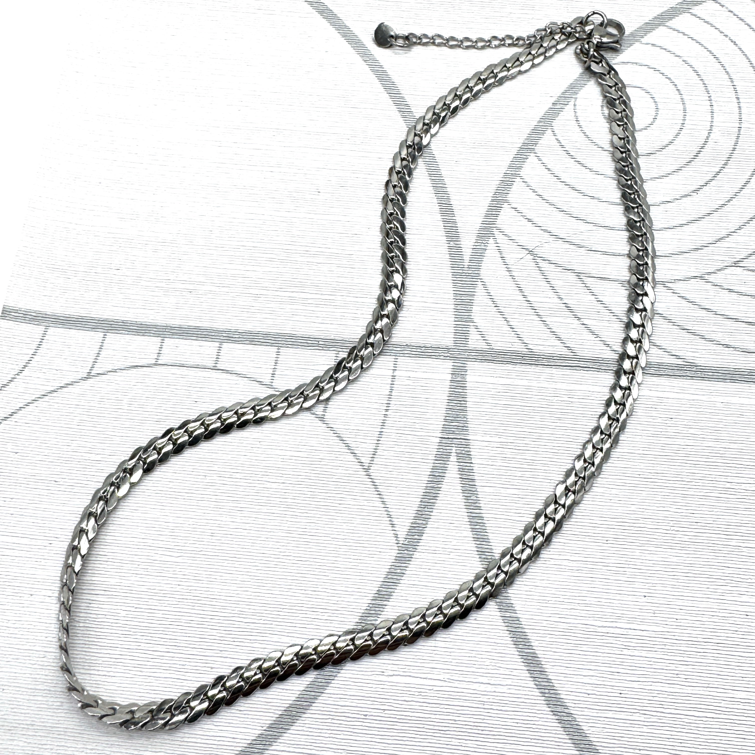 Adjustable silver snake chain necklace on a patterned background.
