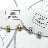Silver and gold crystal hoop earrings on branded earring cards.