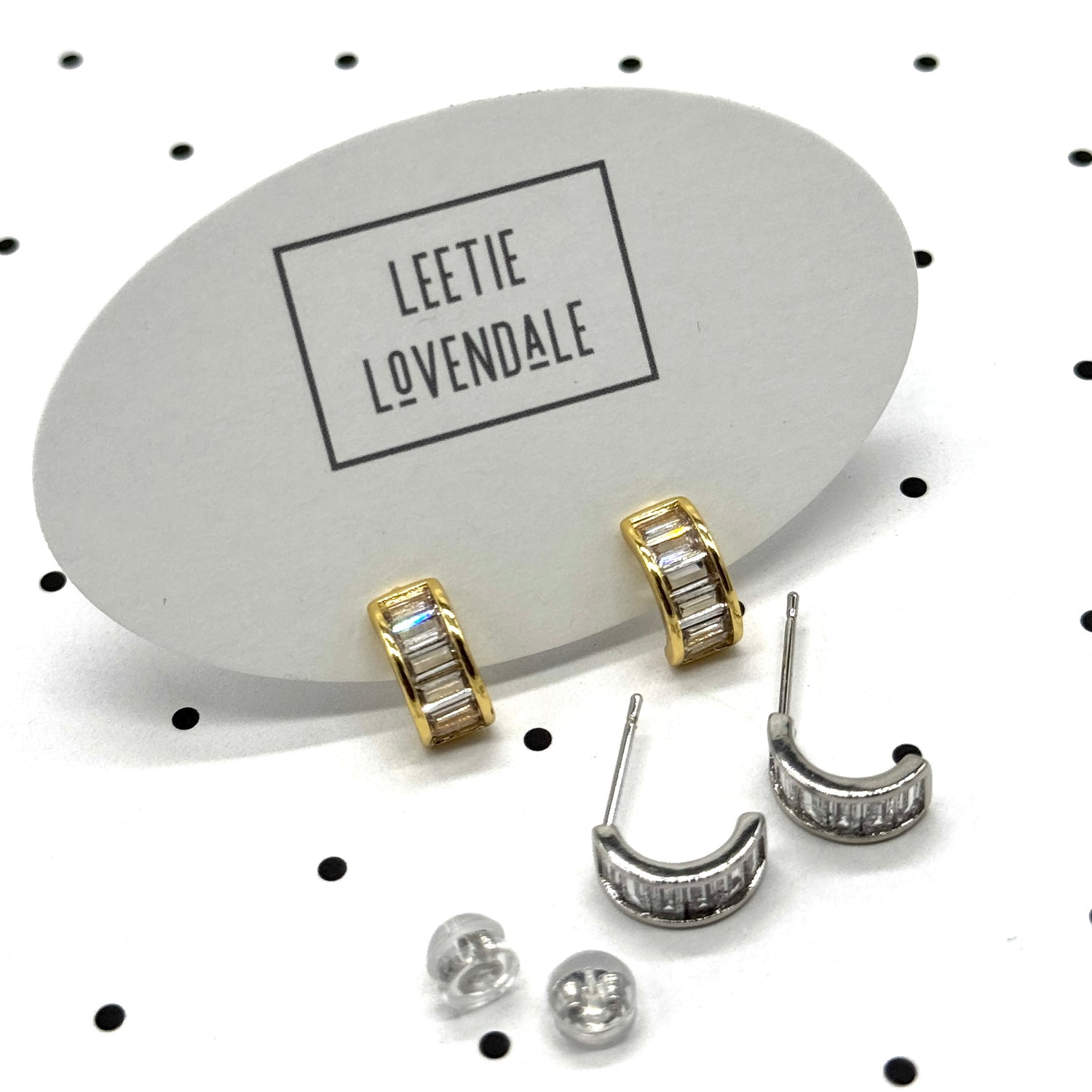 Silver and gold crystal hoop earrings on branded earring cards.