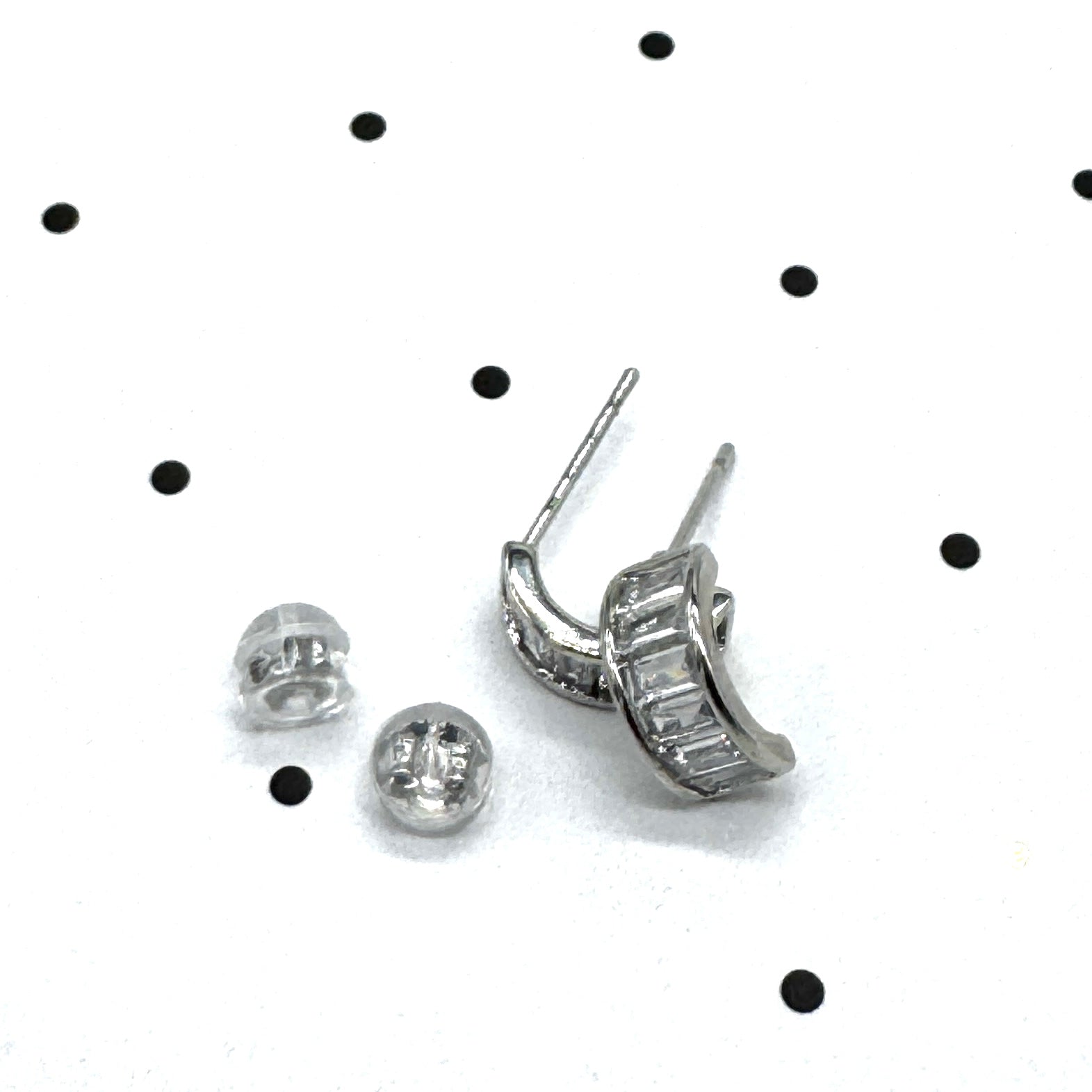 Silver and crystal hoop earrings on a polka dot background.