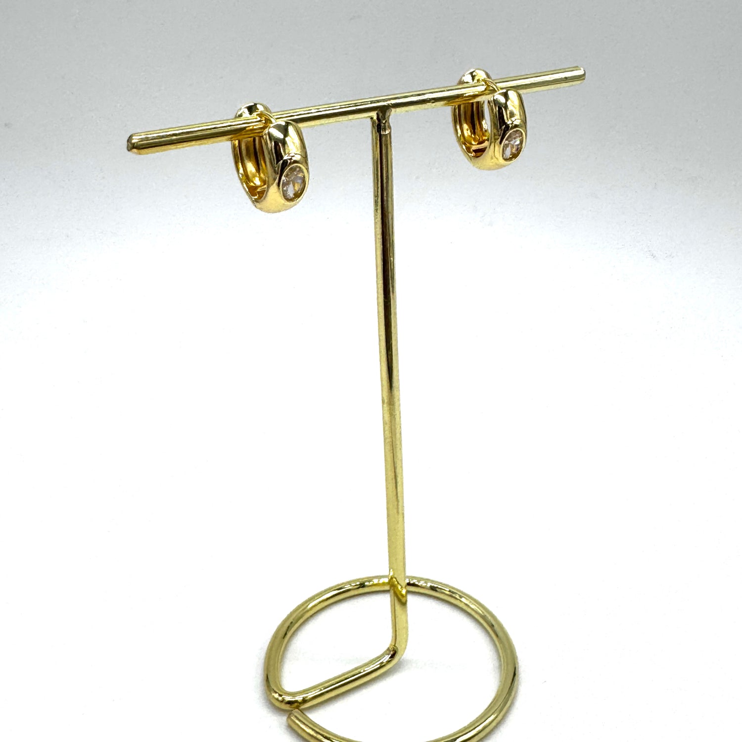 Gold and crystal hoop earrings on a gold stand.