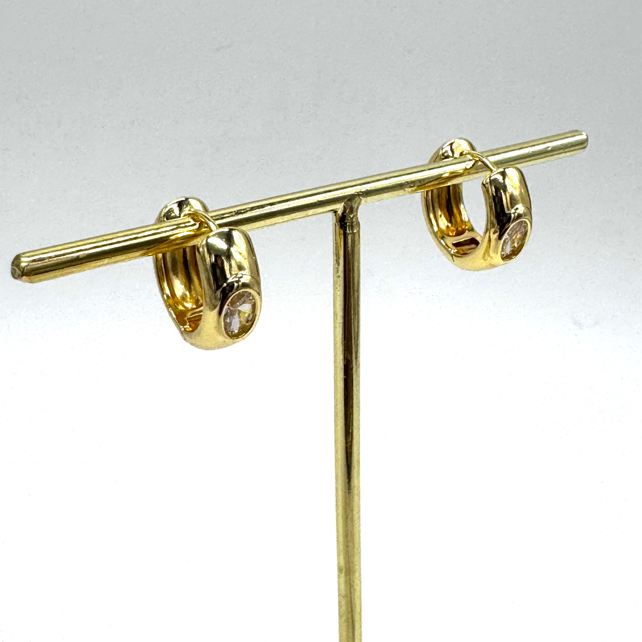Gold hoop earrings with a crystal set in the center of each.