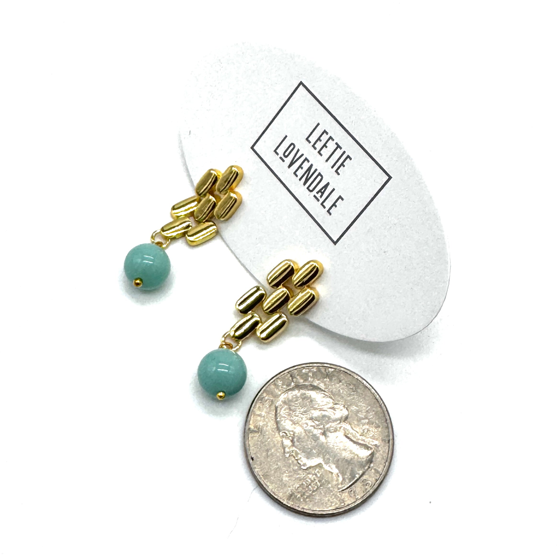 Gold drop earrings with a turquoise glass bead with a quarter for scale.