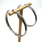 Large silver hoop earrings on a gold stand.