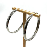 Large silver hoop earrings on a  gold stand.