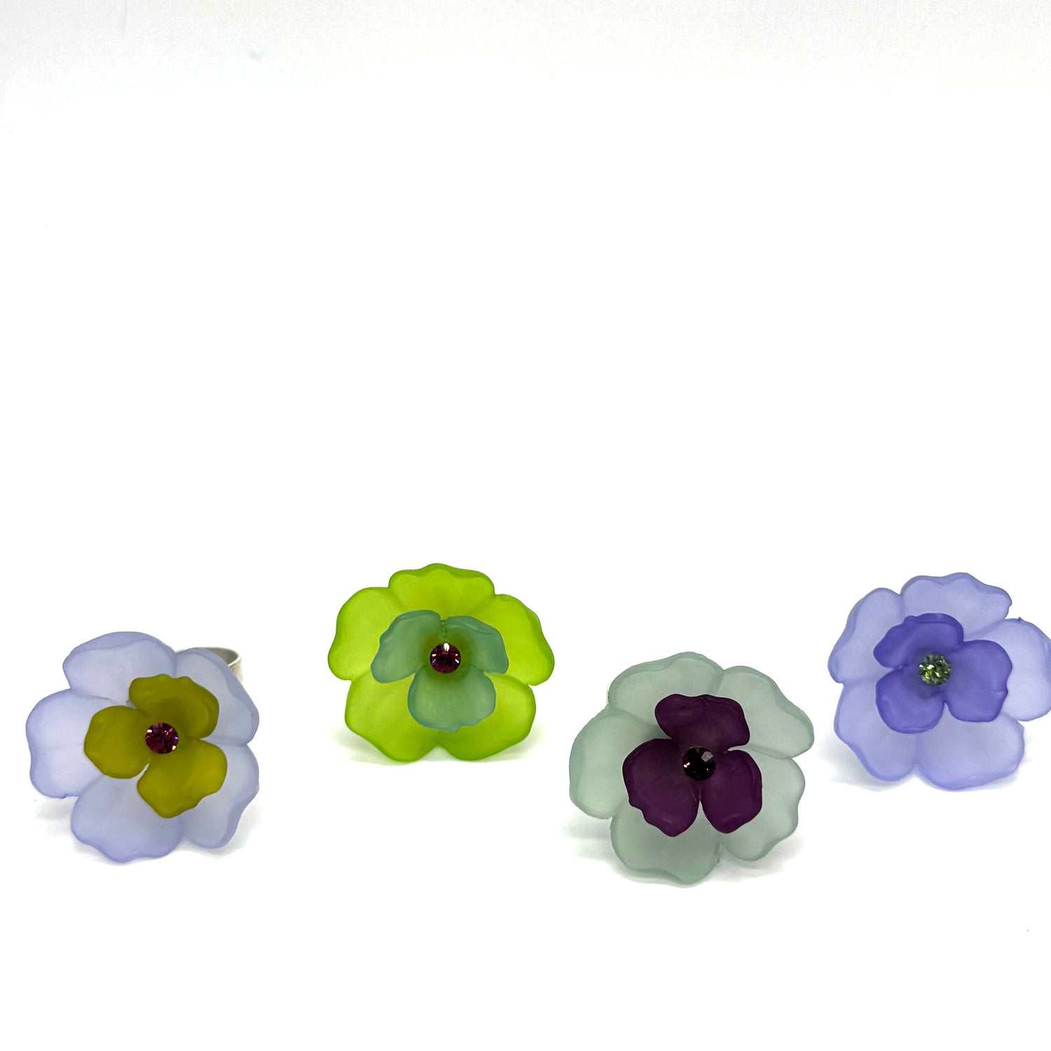 Four colorful floral cocktail rings on a white background.