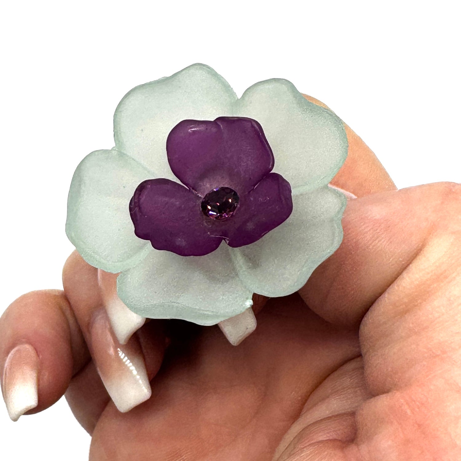 Teal and purple floral cocktail ring held by a hand.