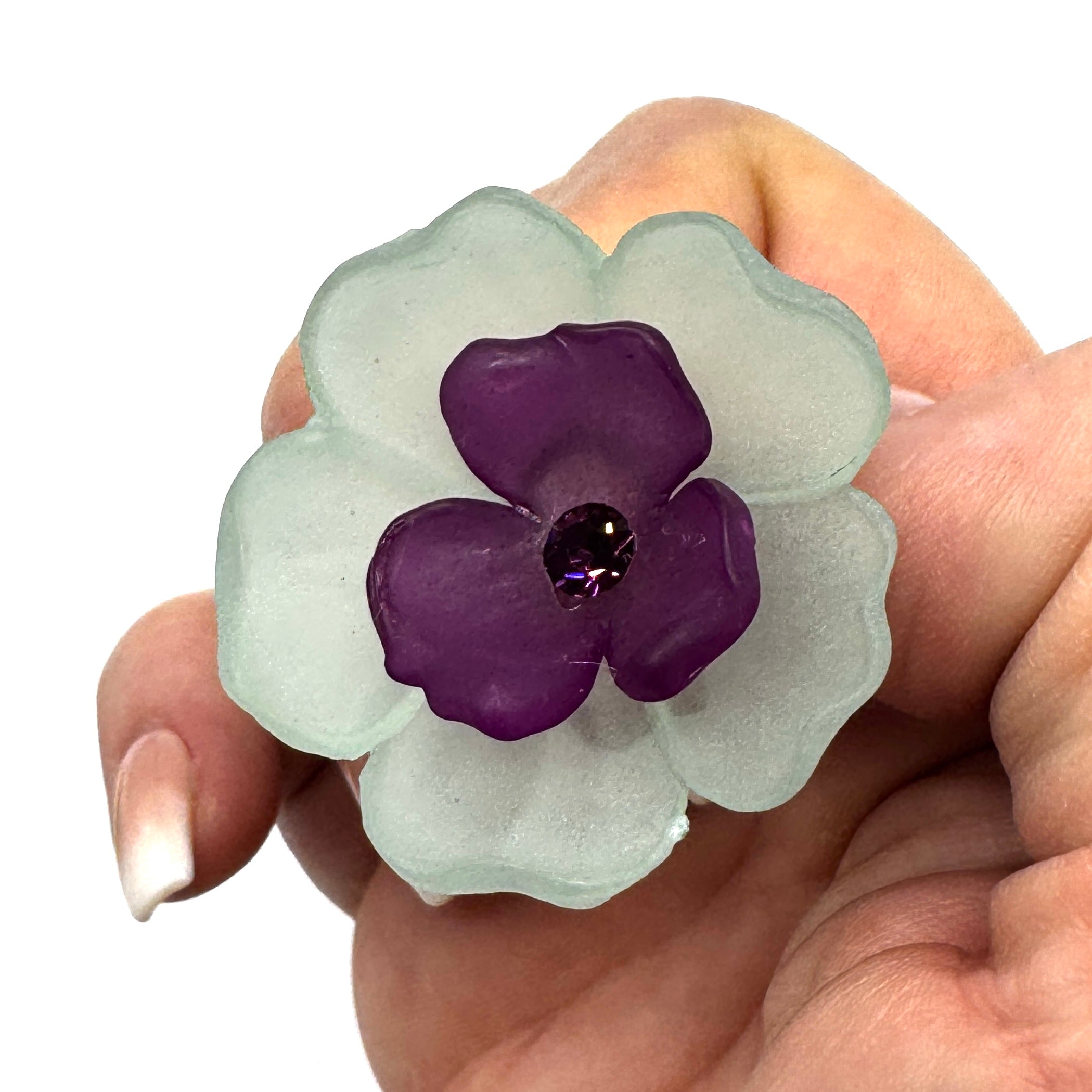 Teal and purple floral cocktail ring held by a hand.