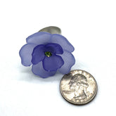 Teal and purple floral cocktail ring on a white background with a quarter for scale.
