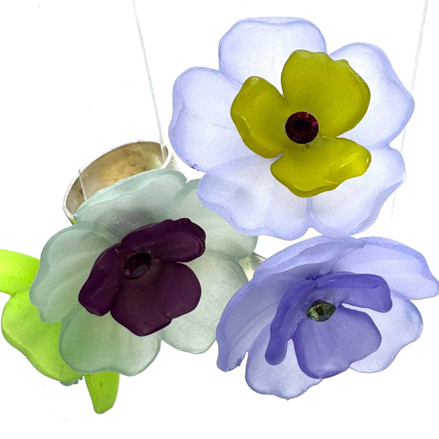 Four colorful floral cocktail rings on a white background.