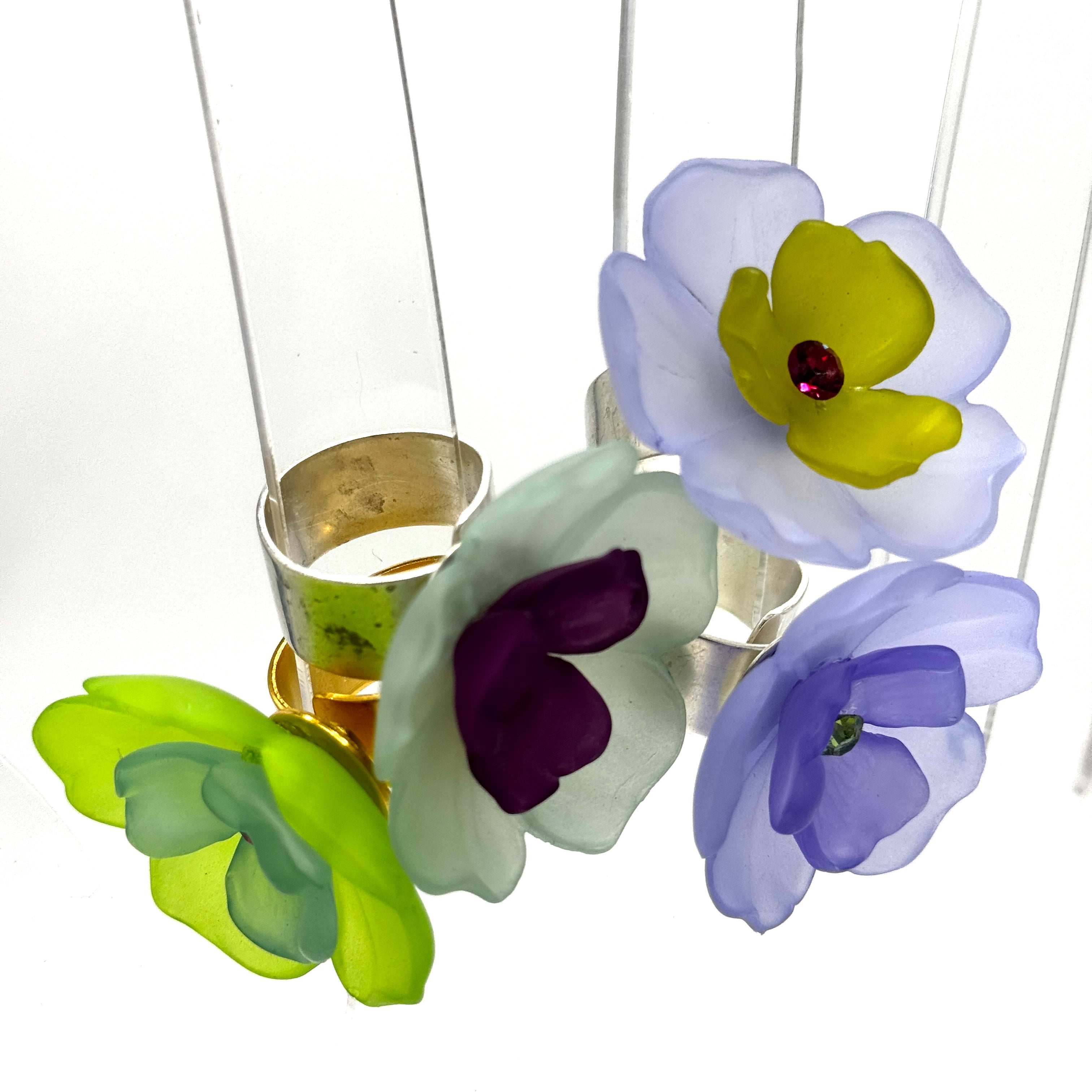 Four colorful floral cocktail rings on a white background.