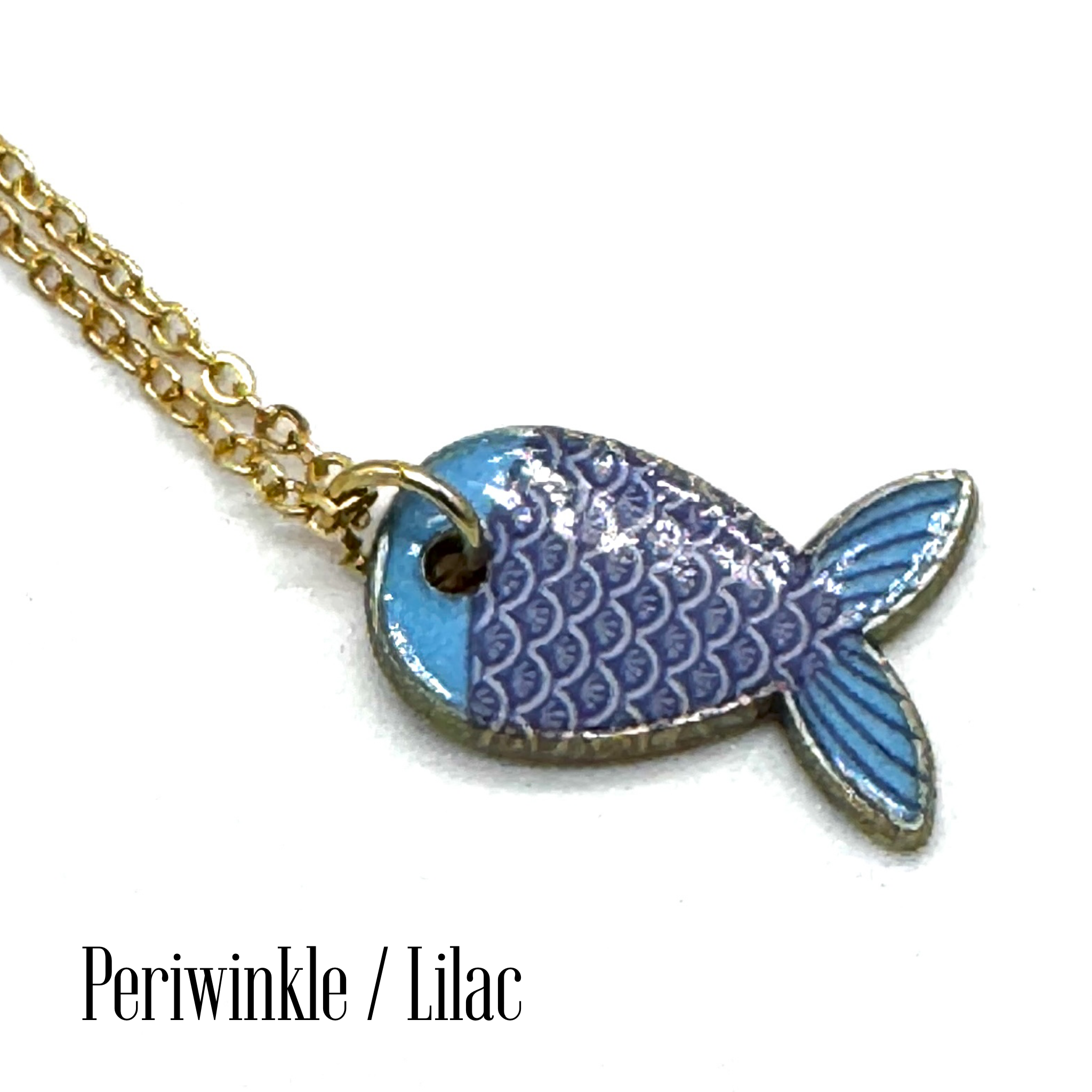 A gold chain necklace with a fish-shaped pendant featuring blue and lilac enamel scales, shown on a white background with the text &