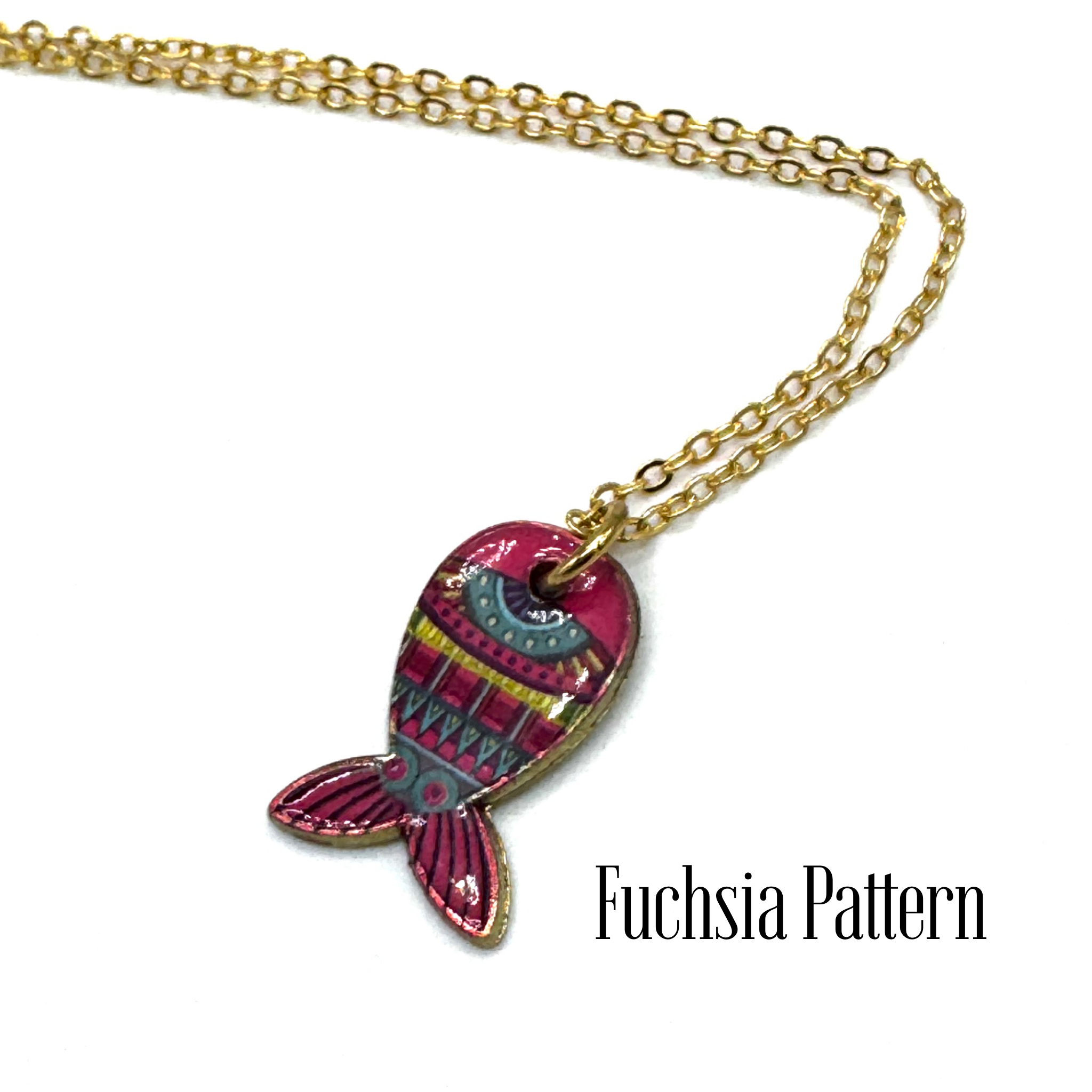 A gold chain necklace with a fish-shaped pendant featuring a vibrant fuchsia and pink pattern, shown on a white background with the text &