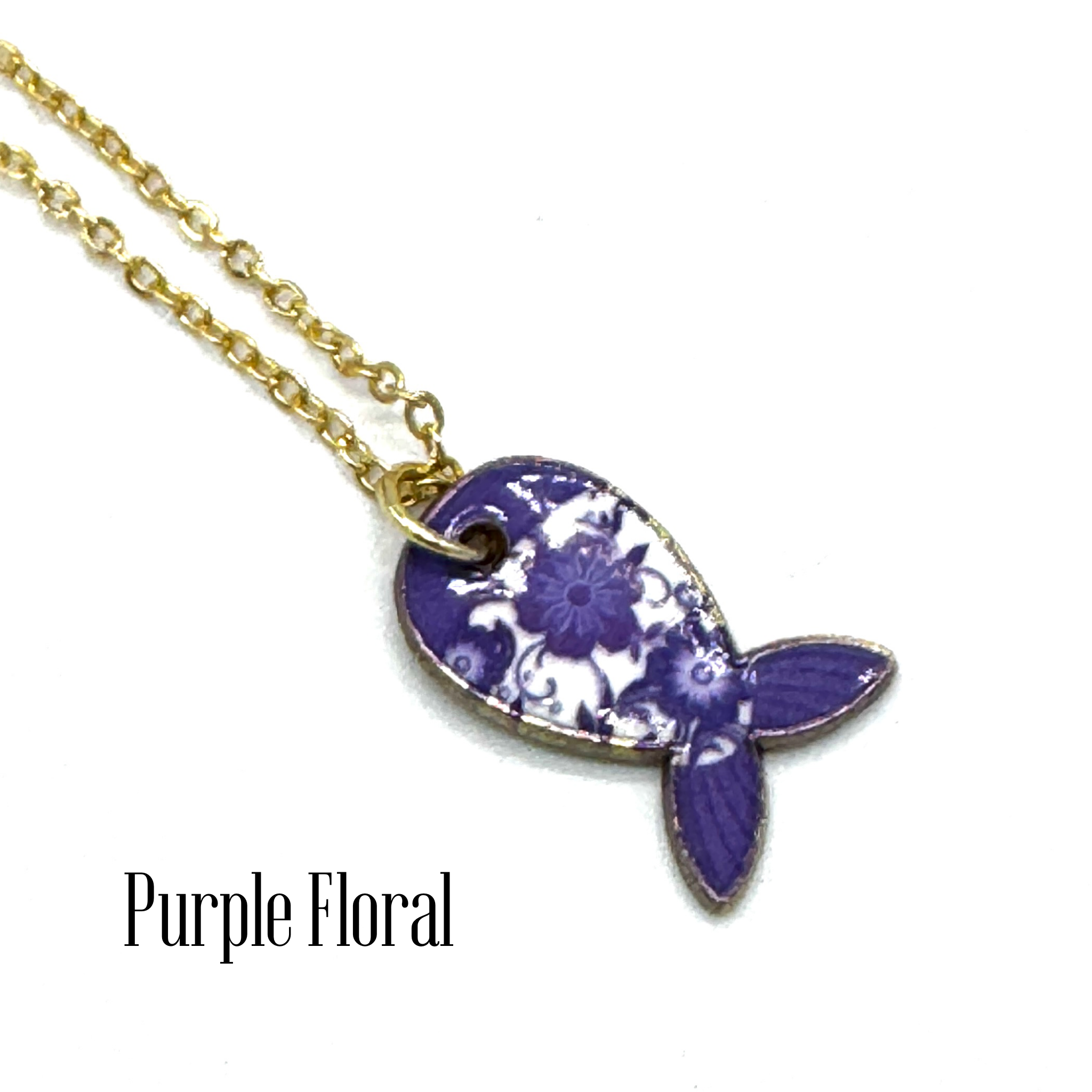 A gold chain necklace with a fish-shaped pendant featuring a purple and white floral pattern, with the text &