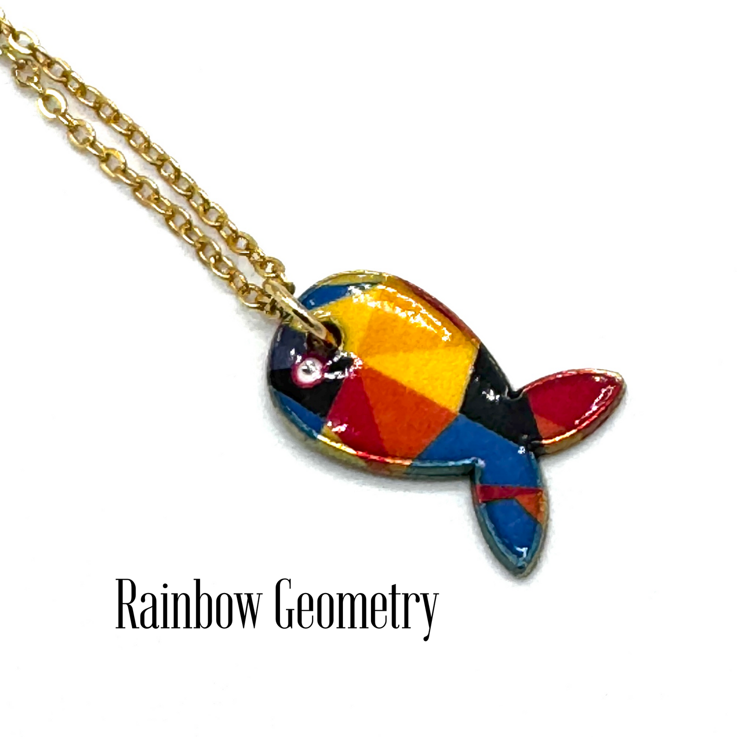 A gold chain necklace with a colorful fish-shaped pendant featuring a geometric rainbow pattern of red, orange, yellow, blue, and black, displayed on a white background with the text &