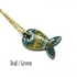 A gold chain necklace with a stylized fish pendant featuring teal, green, and gold mosaic detailing, shown on a white background with the text &