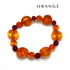 An orange beaded bracelet with translucent spiral-shaped beads and dark red round accent beads, displayed on a white background with the word &