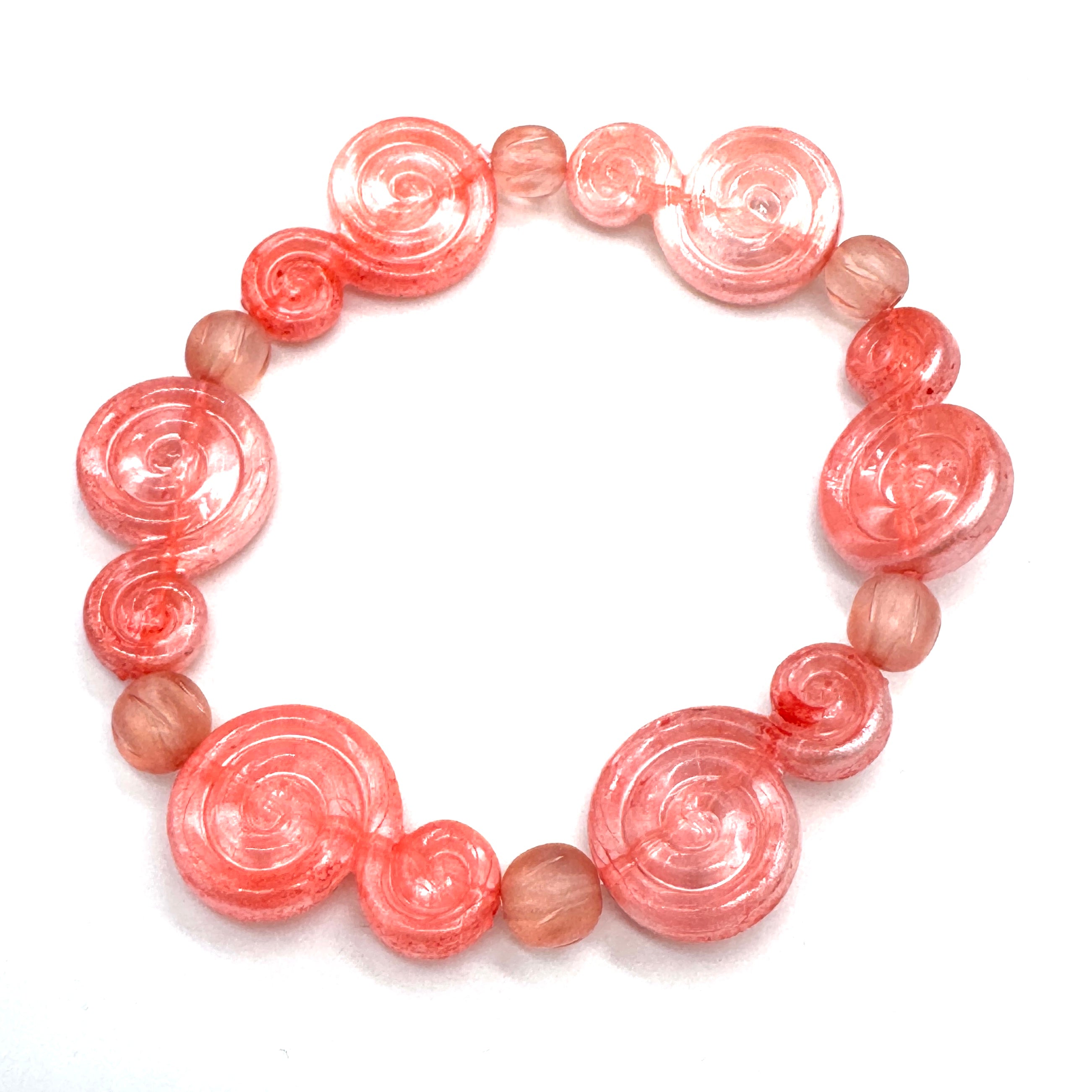 A beaded stretch bracelet featuring translucent pink spiral beads and smooth, round dusty pink beads, displayed on a clean white background.