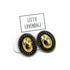 A pair of oval stud earrings with a shiny gold center and a dark bronze textured border, displayed on a white backing card with the brand name &