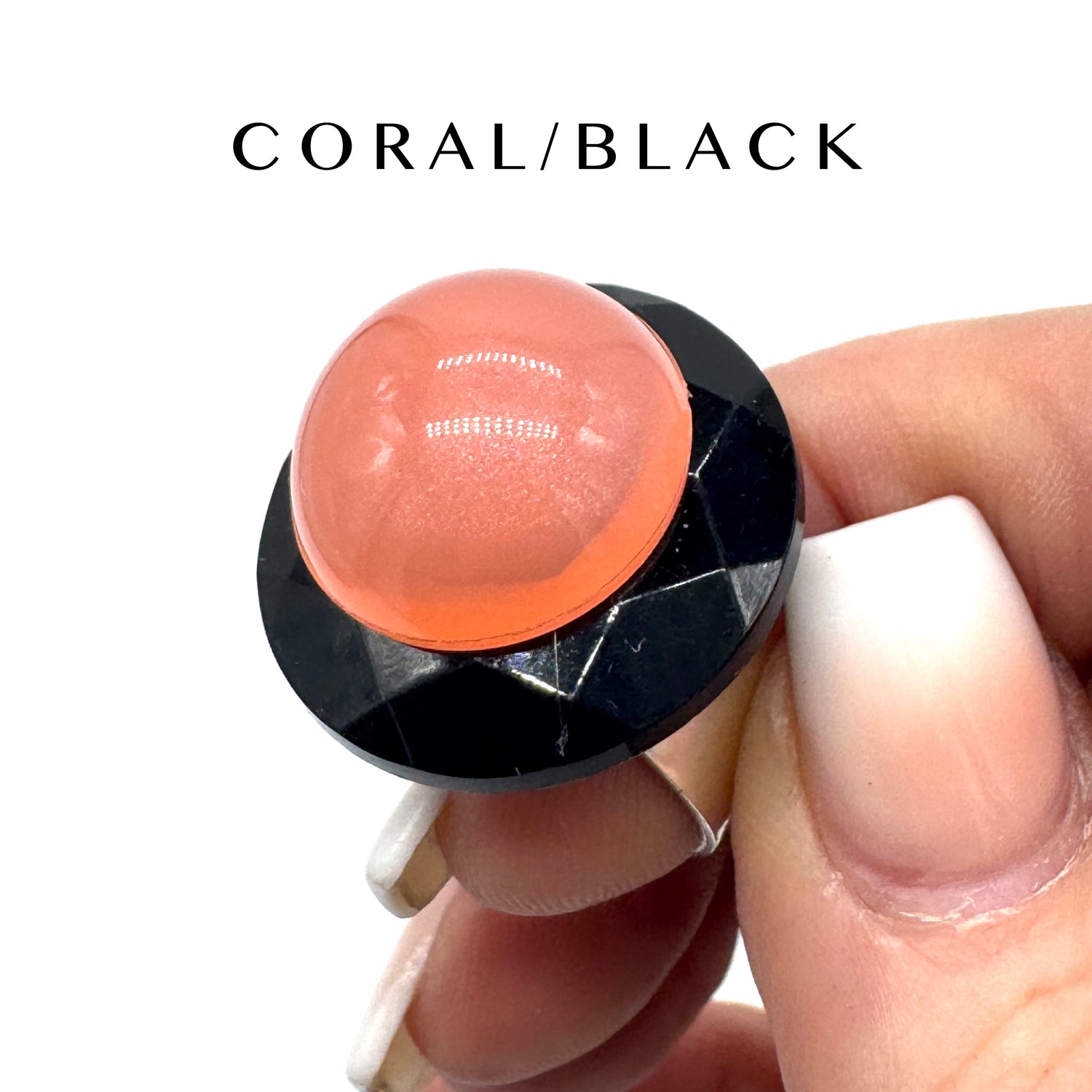 Hand holding a coral and black ring  on a white background