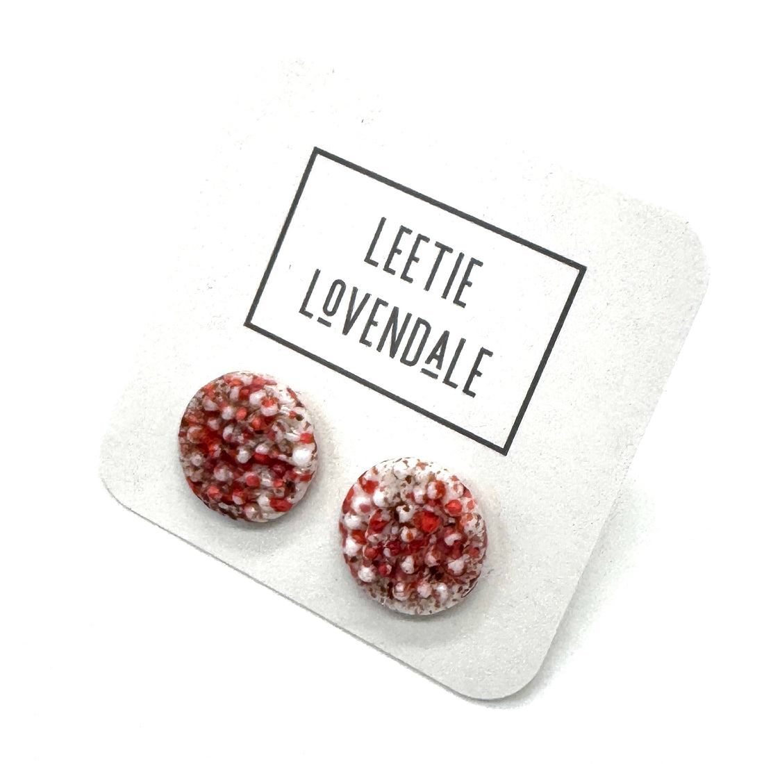 A pair of textured round stud earrings in a speckled hot pink and white, displayed on a white card with the text &